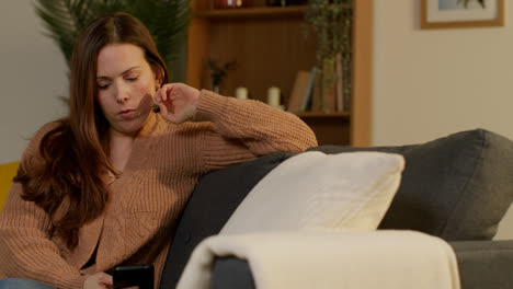 Woman-Sitting-On-Sofa-At-Home-Using-Mobile-Phone-To-Check-Social-Media-Message-And-Scrolling-Online-1